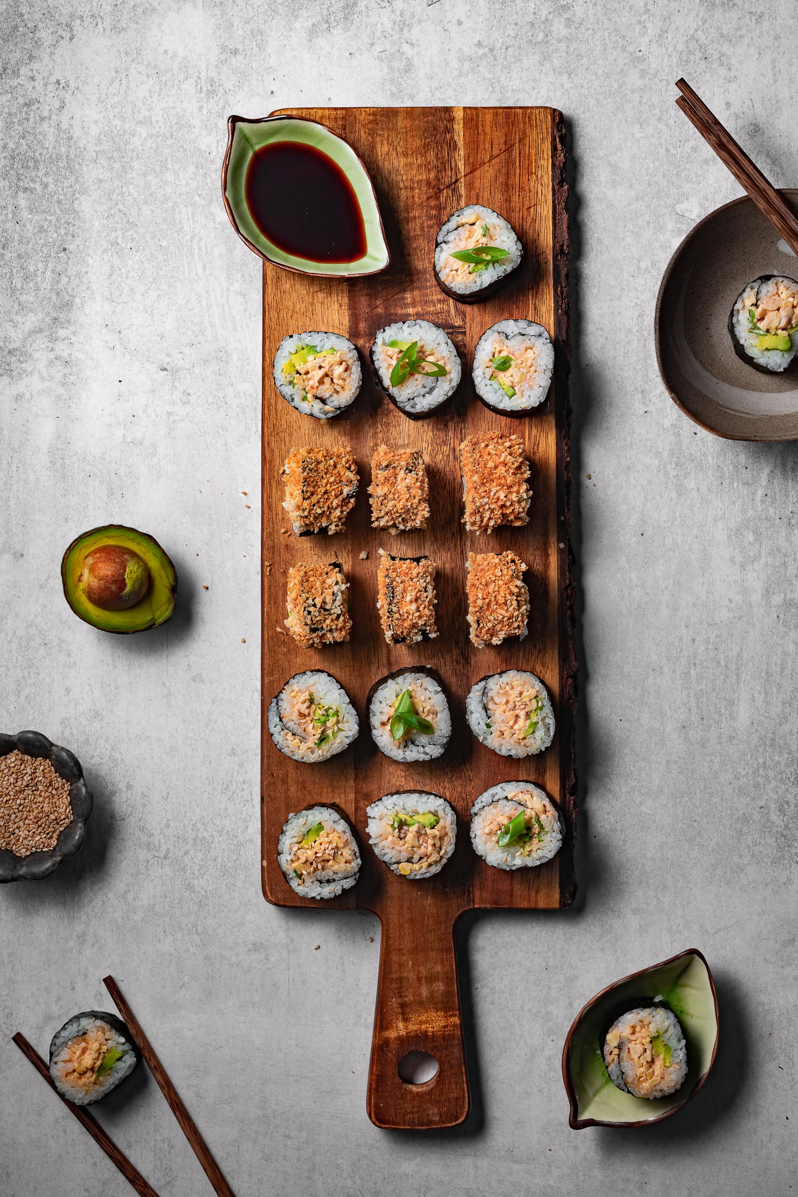 Sushi displayed on a long cutting board.