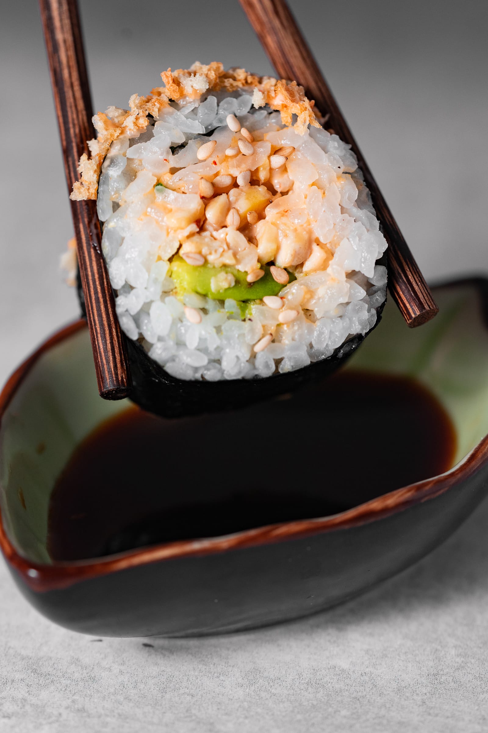 Tempeh crunch roll being dipped in soy sauce.