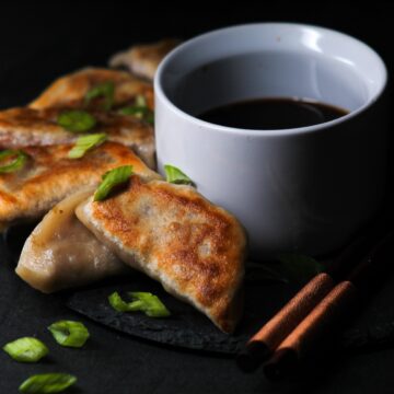 Crispy dumplings on a plate garnished with scallions.