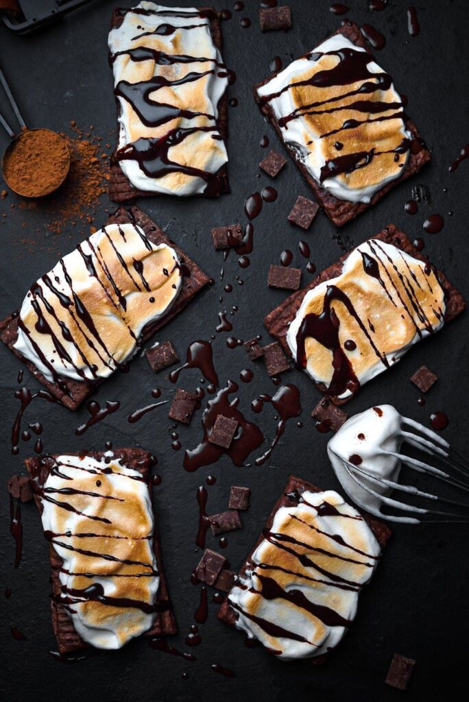hot cocoa pop tarts surrounded by chocolate, cocoa powder and meringue topping.