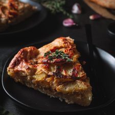 Slice of the potato galette on a small plate garnished with fresh thyme.