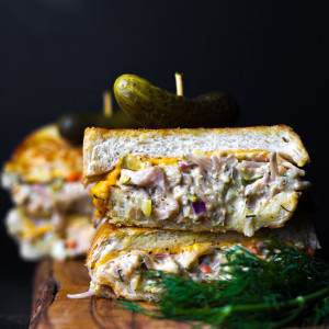 Jackfruit tuna melt stacked with a pickle on top.