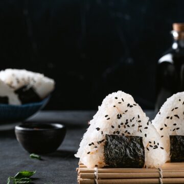 Onigiri covered in black sesame seeds with green onion.