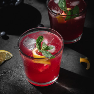 Kombucha cocktail in a glass cup garnished with mint and lemon twirl.