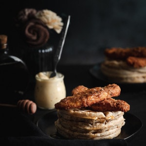 Waffles stacked with vegan fried chicken on top with whipped butter.