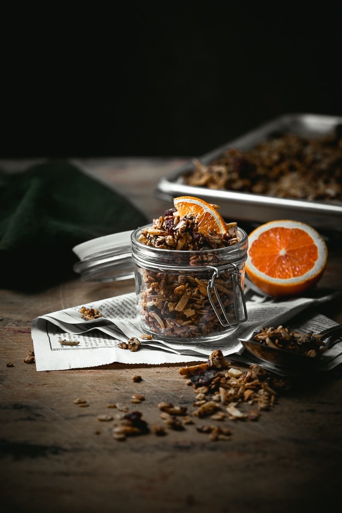 Chocolate orange granola in a small jar with orange slice garnish.