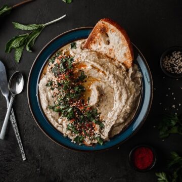 Baba Ganoush served in a shallow bowl with bread and fresh herbs.