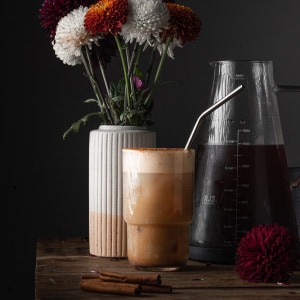 Pumpkin cold brew with flowers in the background and cold brew.