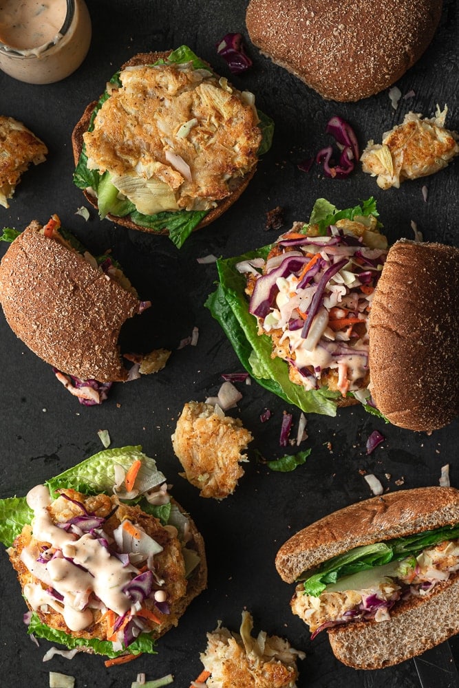Vegan crab cake sandwiches topped with slaw, lettuce and mayo.