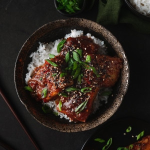 spicy gochujang tofu in a bowl with rice and green onion.