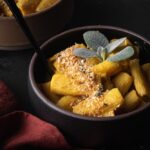 bowl of pumpkin Mac and cheese with breadcrumbs and sage garnish.