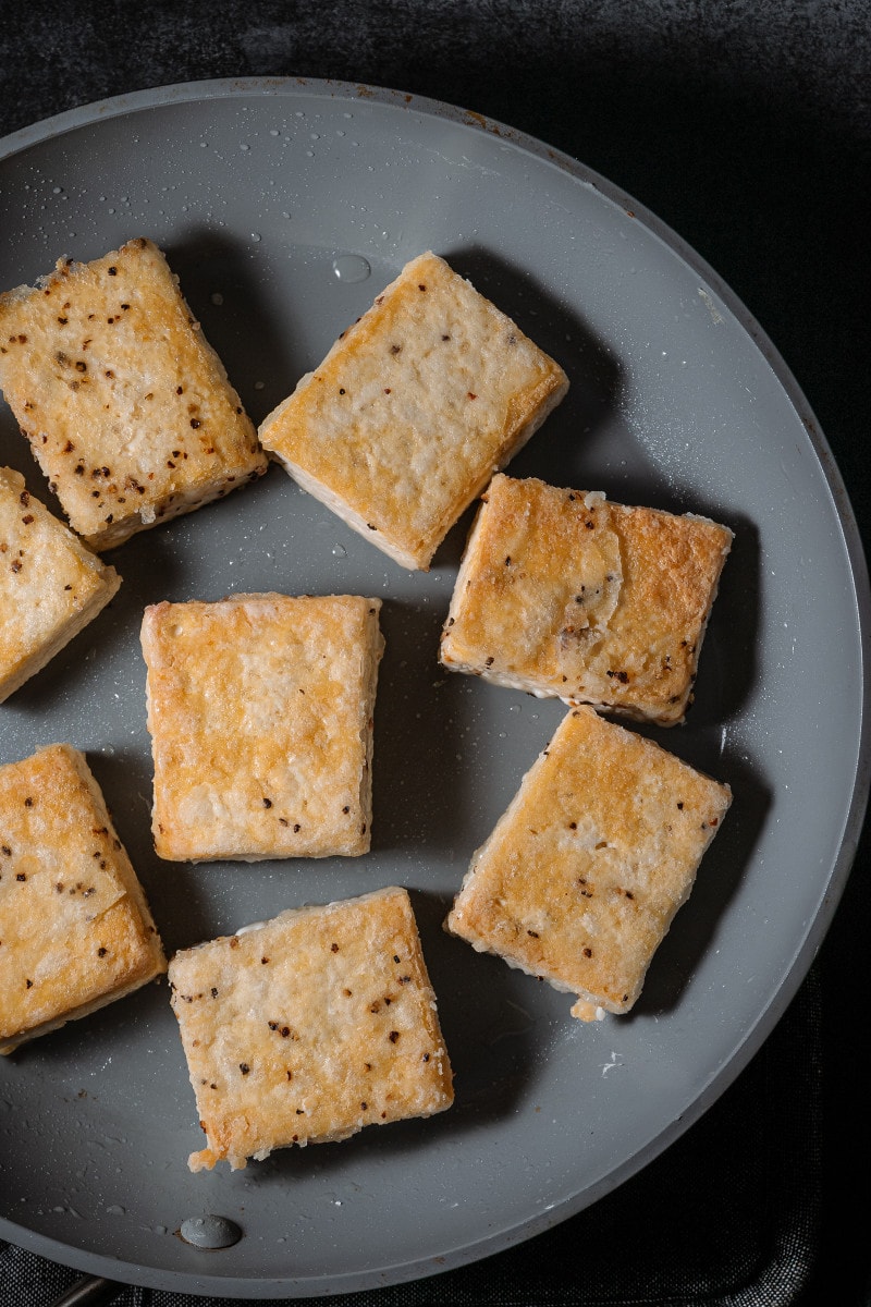 Crispy golden tofu in a frying pan.