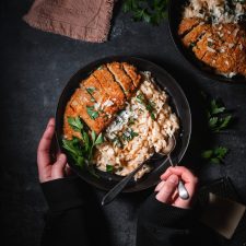 Bowl of Creamy Vegan Garlic Parmesan Orzo paired with crispy vegan chicken and parsley.