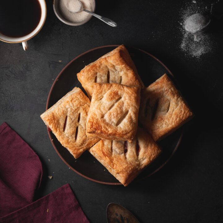 guava cheese pastries on a plate surrounded by guava, coffee, sugar, and cream