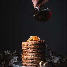 stack of spiced waffles topped with banana and maple syrup