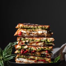 Stack of Tofu Pesto Grilled Cheese Sandwiches garnished with basil.