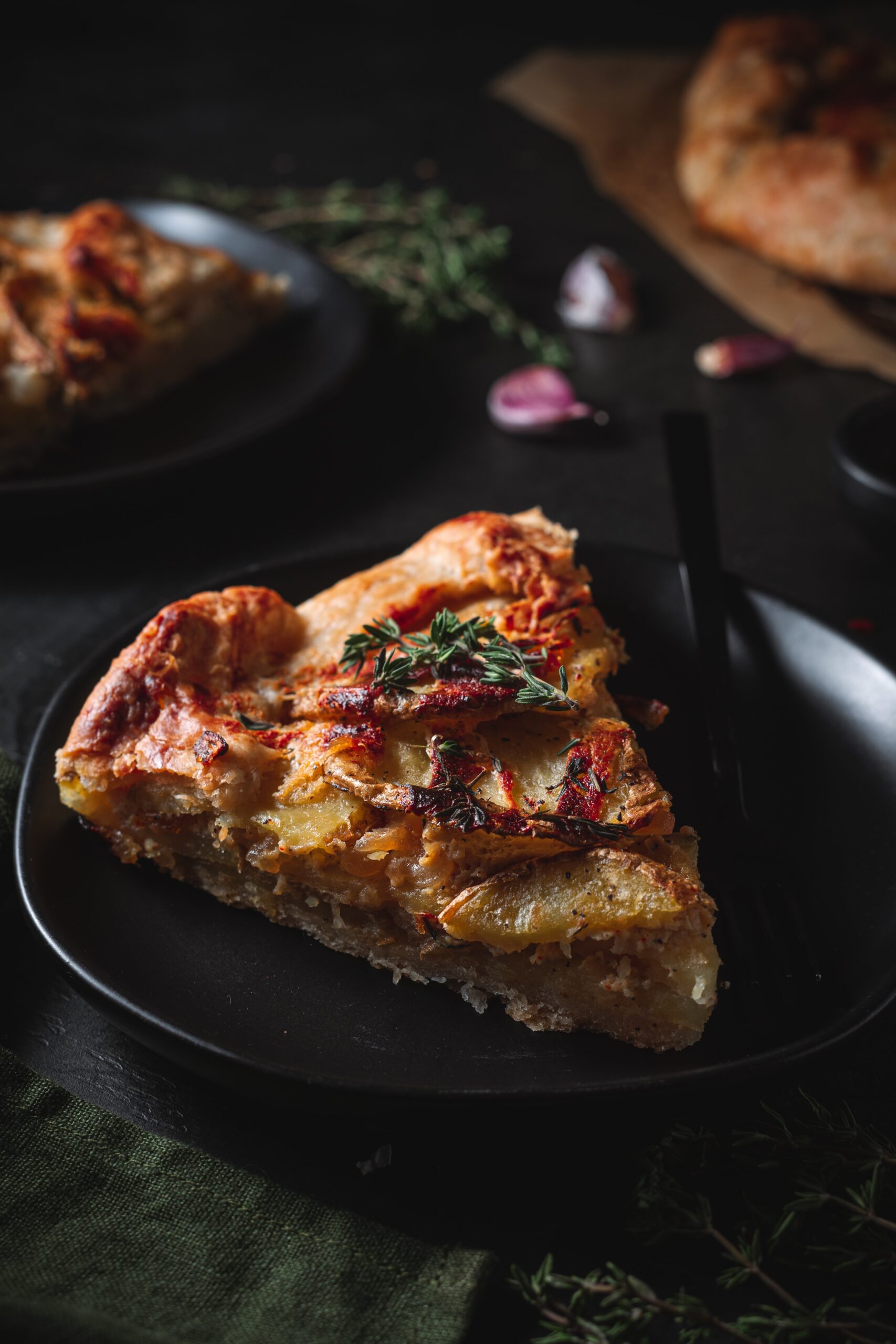 Slice of caramelized onion galette on a serving plate with fresh thyme garnish.