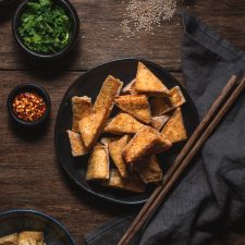 Cooked Crispy Tofu cut in to triangles on a serving plate.