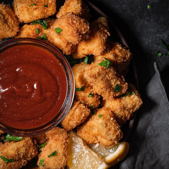 Tofu nuggets on a serving tray with bbq sauce and fresh parsley.