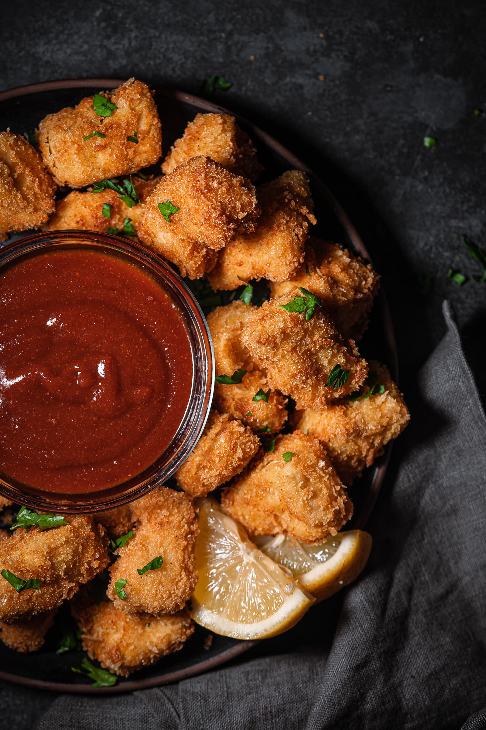Tofu nuggets on a serving tray with bbq sauce and fresh parsley.
