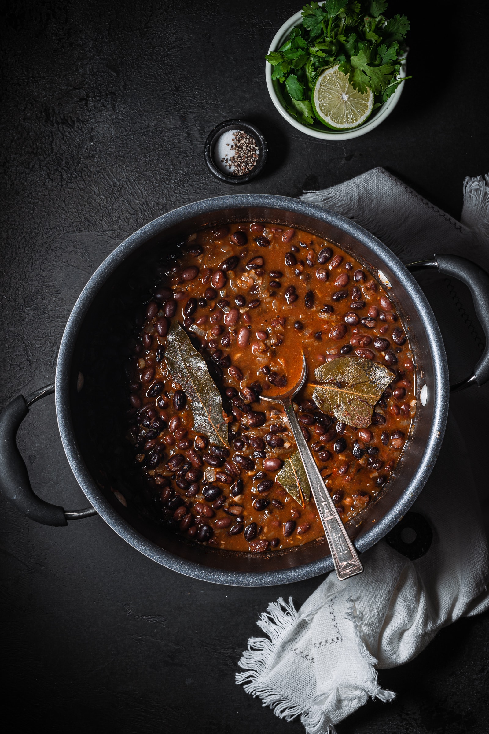 Chipotle black beans in pot with bay leaves.