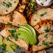 close up of vegan crispy tacos with avocado and sour cream.