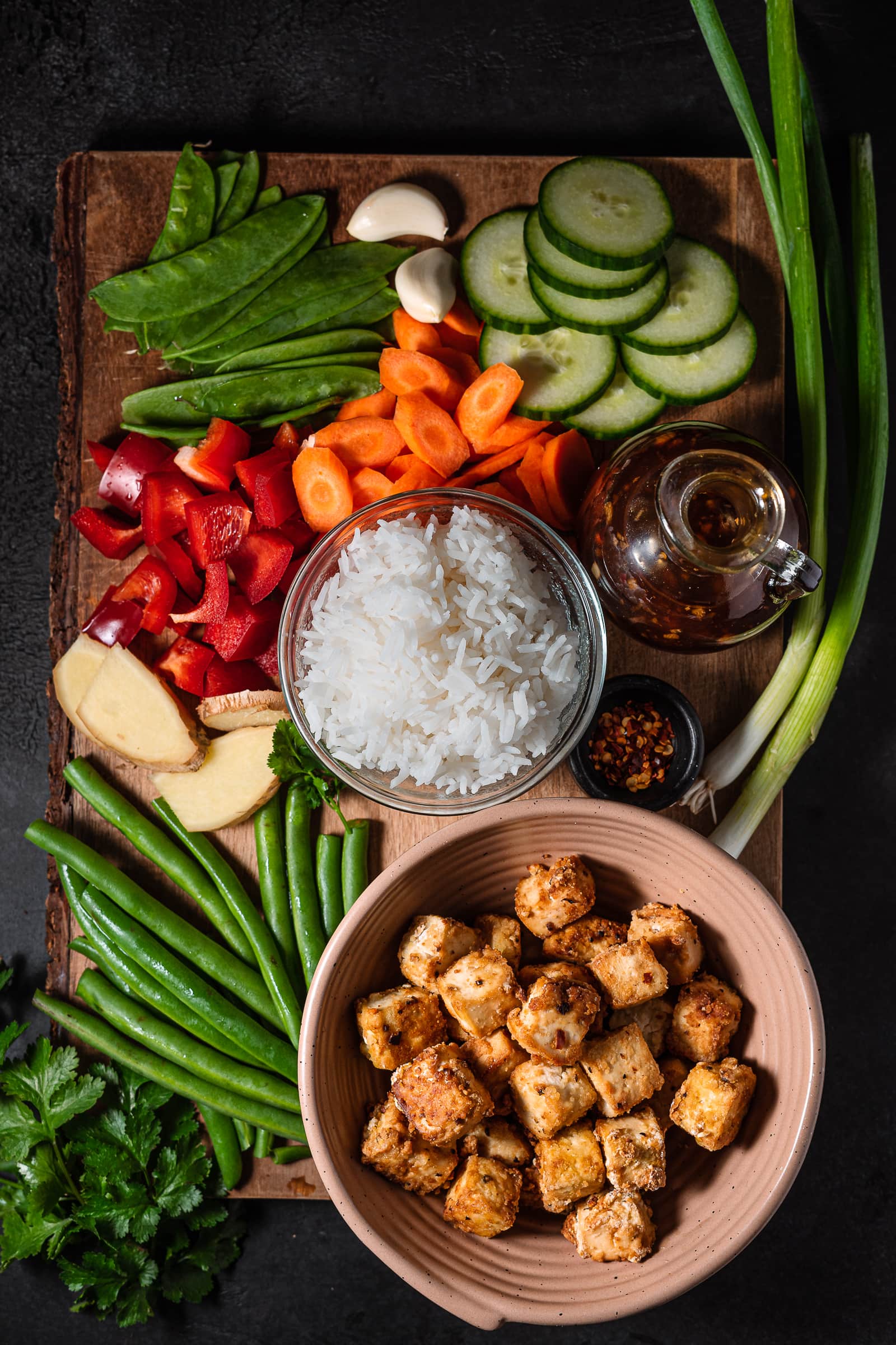 Vegetables and tofu on a wooden cutting board.