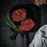 Vegan steak on a grill pan with rosemary garnish.