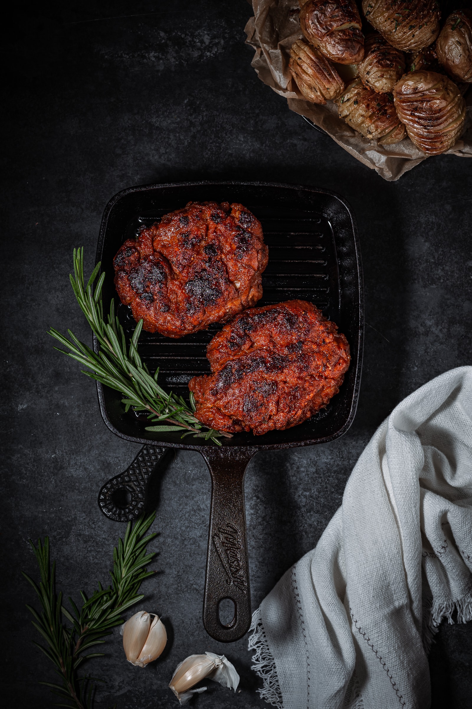 Vegan steak on a grill pan with rosemary garnish.
