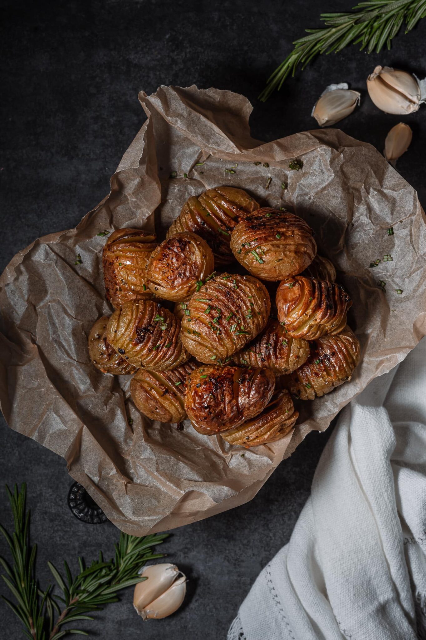Hasselback potatoes with fresh rosemary on parchment.