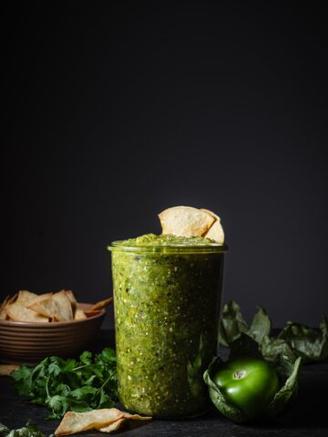 tomatillo green chili salsa in a glass jar with chips.
