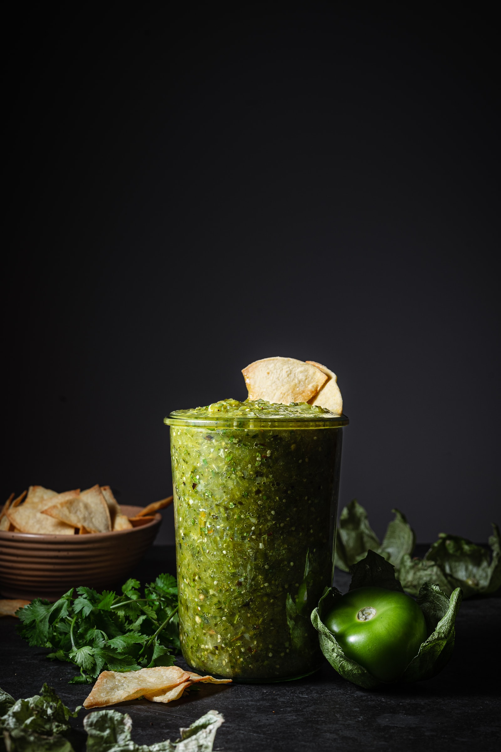 tomatillo green chili salsa in a glass jar with chips.