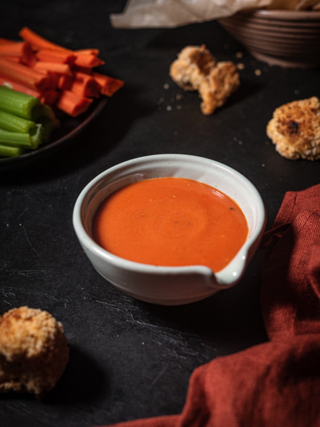 buffalo sauce in serving container with crispy cauliflower.