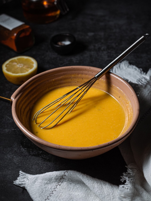 vegan honey mustard dressing in a bowl with a whisk.