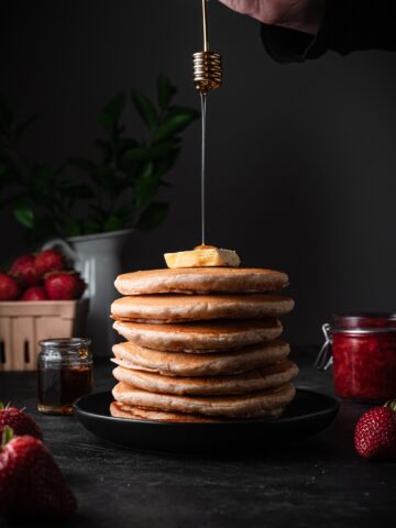 Big stack of vegan pancakes with a pat of butter and syrup drizzle.