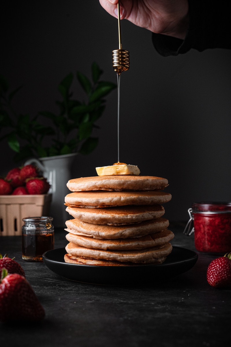 Big stack of vegan pancakes with a pat of butter and syrup drizzle.