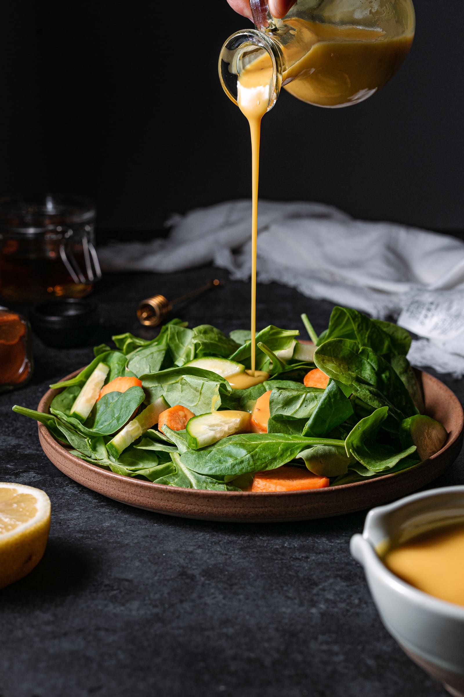 honey mustard being drizzled over spinach.