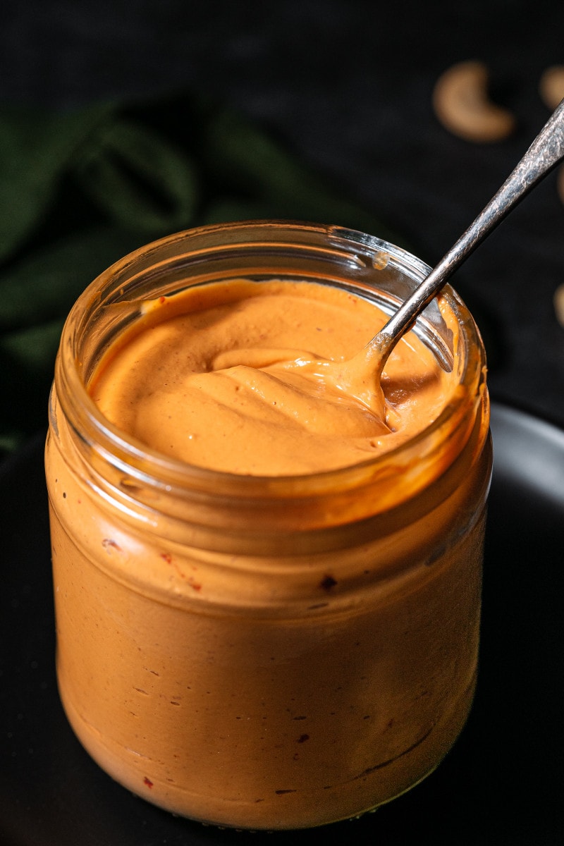 Close up of a spoon in the jar of vegan aioli.