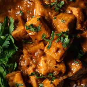 Close up of butter chicken with tofu over basmati rice, cilantro and fresh naan.