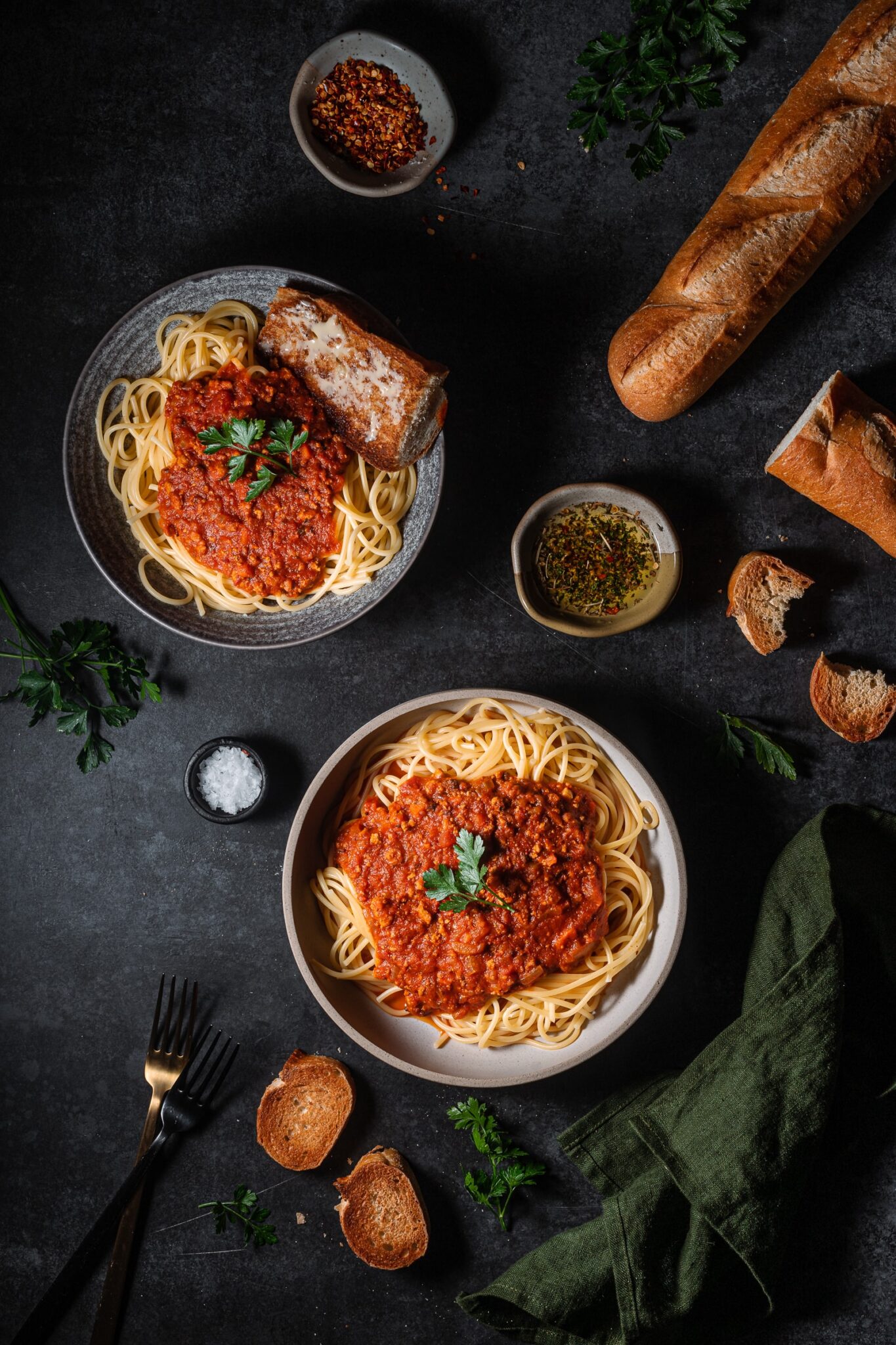 Tofu bolognese over spaghetti with baguette and parsley.
