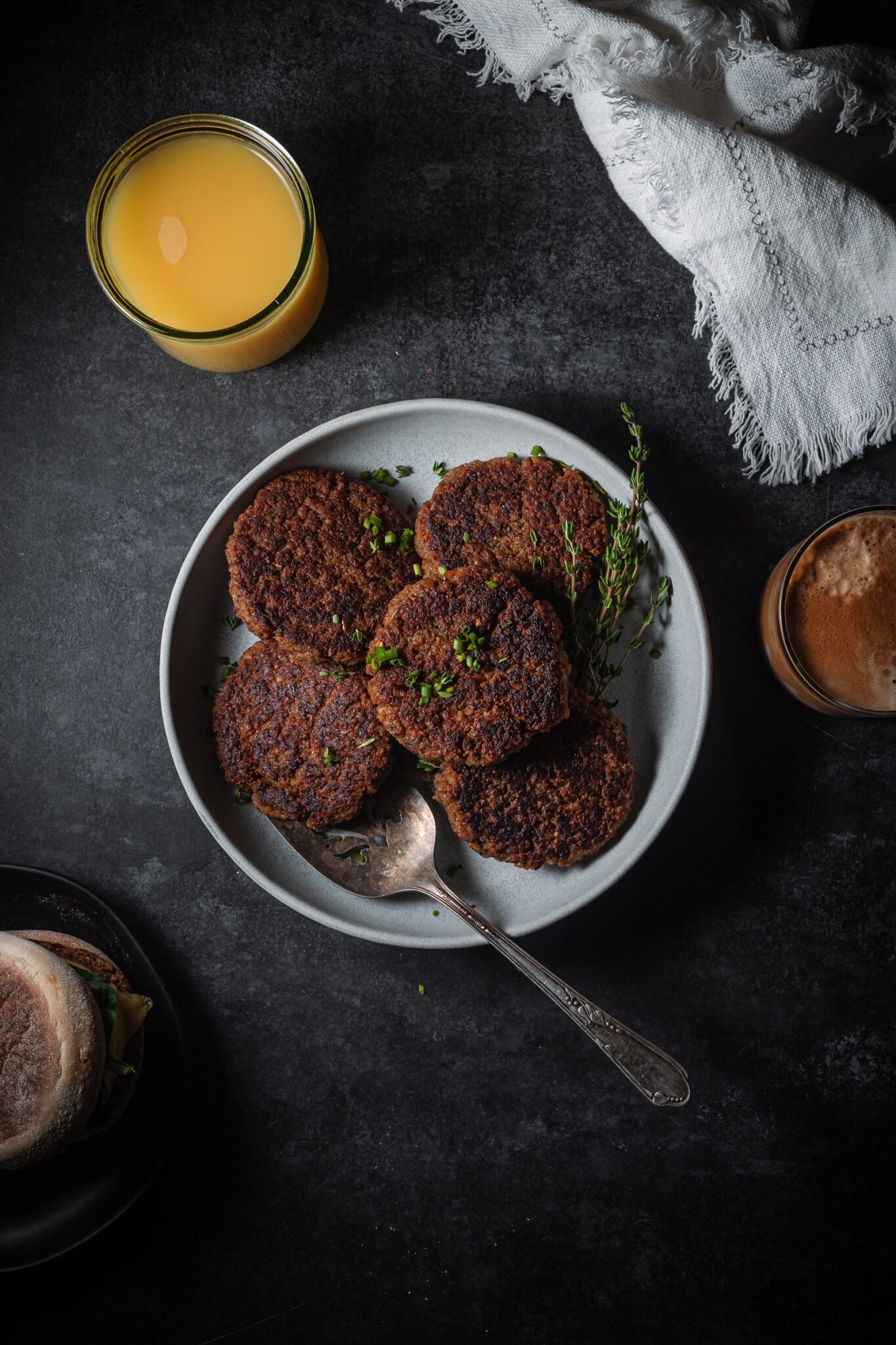 Vegan breakfast sausages on a plate with a serving spatula. Served with orange juice and coffee.
