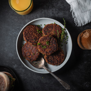 Vegan breakfast sausages on a plate with a serving spatula. Served with orange juice and coffee.
