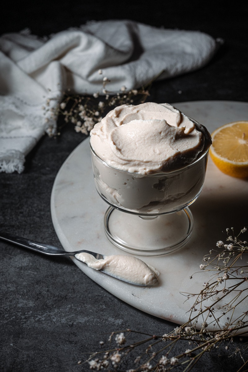 Vegan mascarpone in a small trifle dish with a spatula.