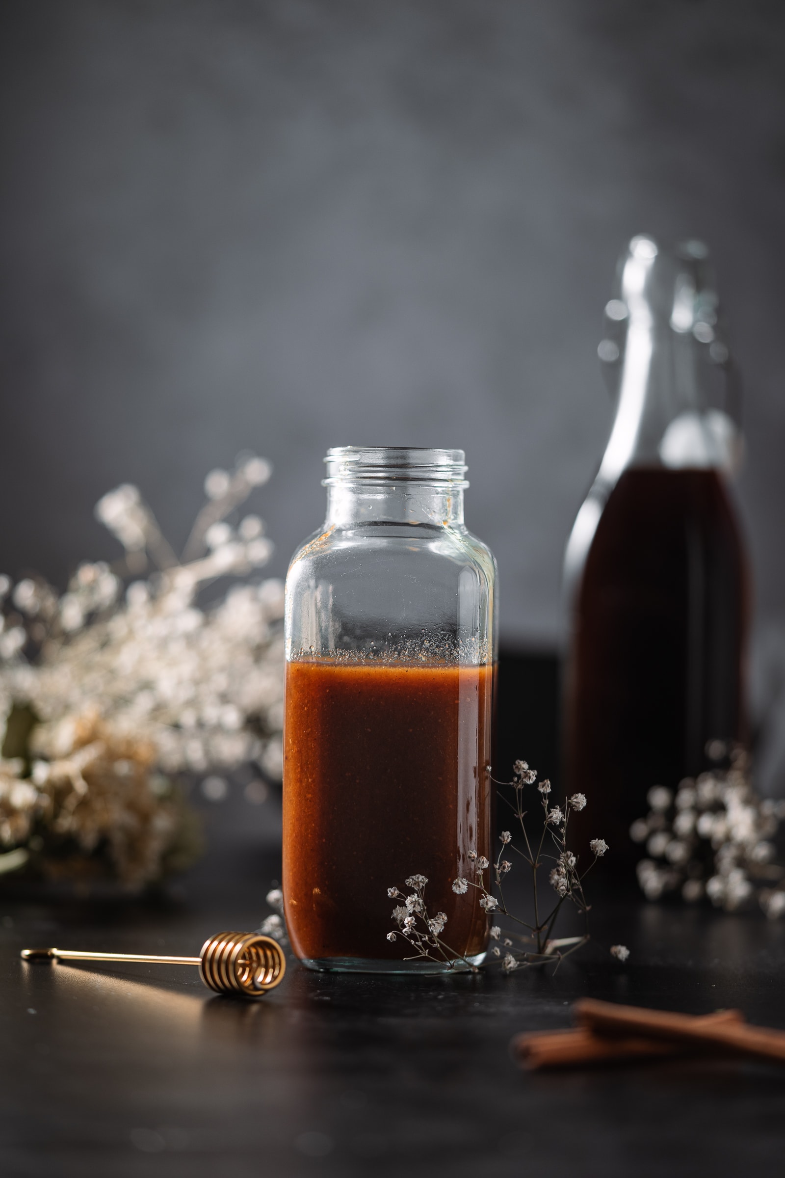 Pumpkin spice simple syrup in a glass jar surrounded by dried flowers and a container of cold brew.
