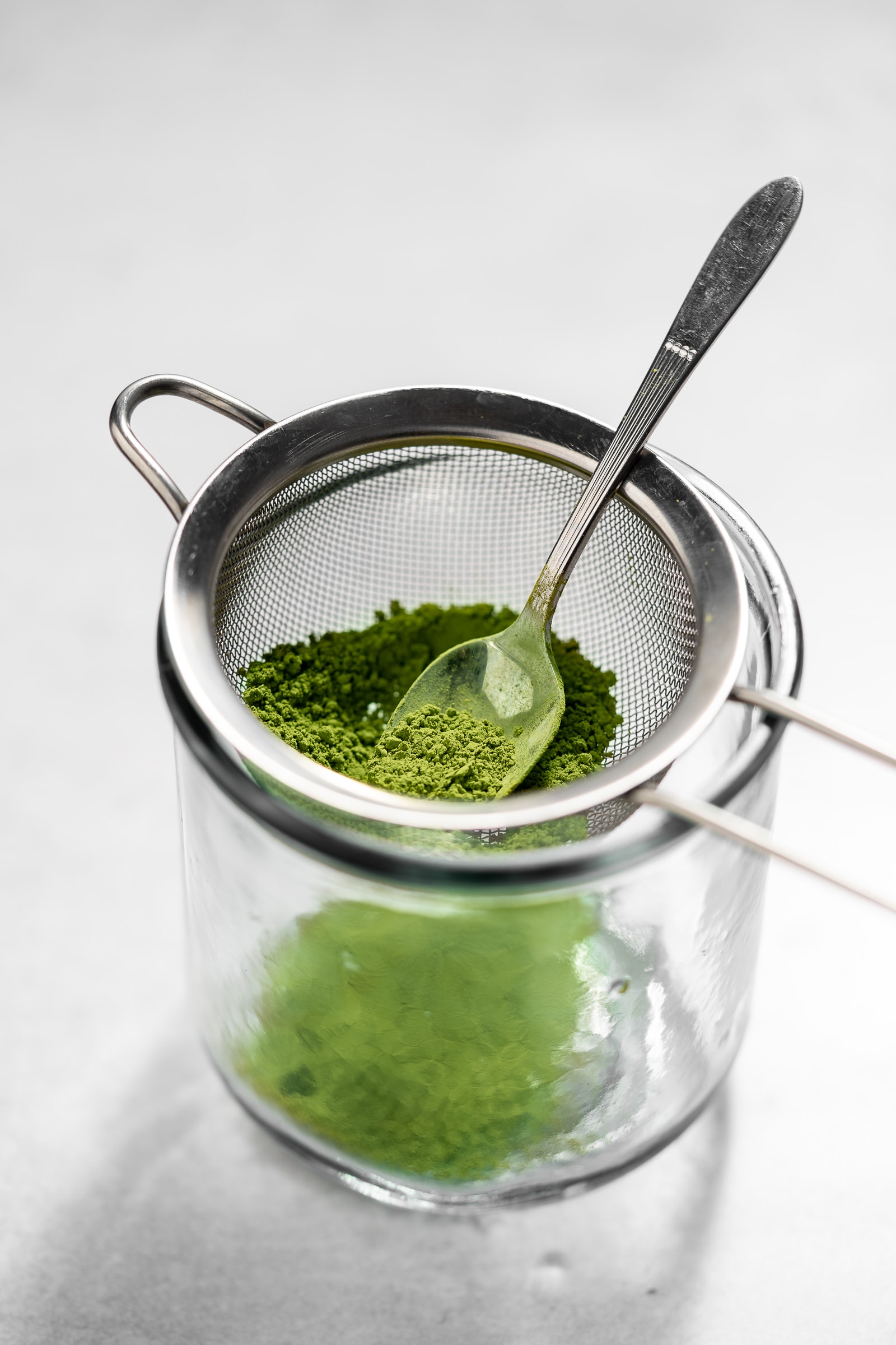 Matcha being shifted through a mesh strainer.