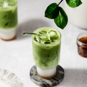 Matcha layered with simple syrup and oat milk in a glass.
