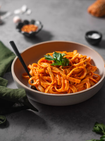 bowl of red pepper pasta garnished with parsley.