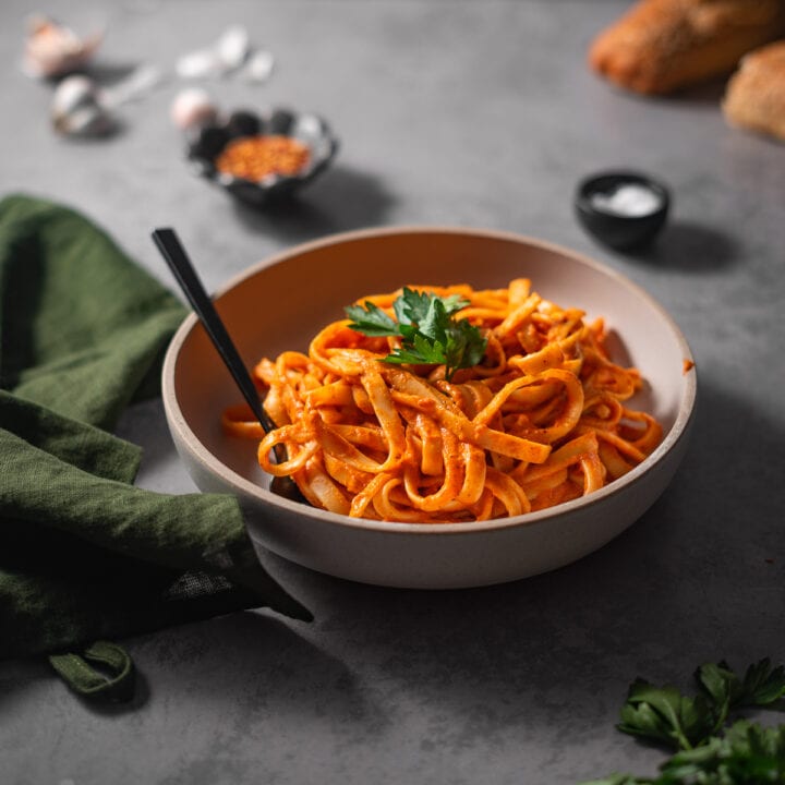 bowl of red pepper pasta garnished with parsley.