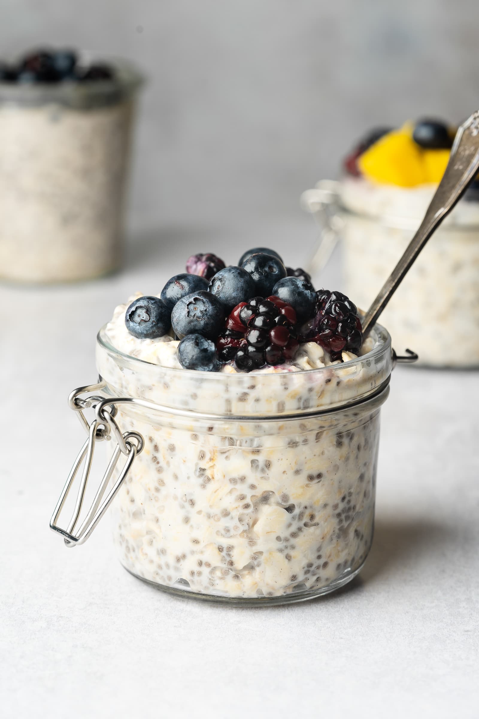 Small glass jar of almond milk overnight oats topped with blueberries and blackberries.