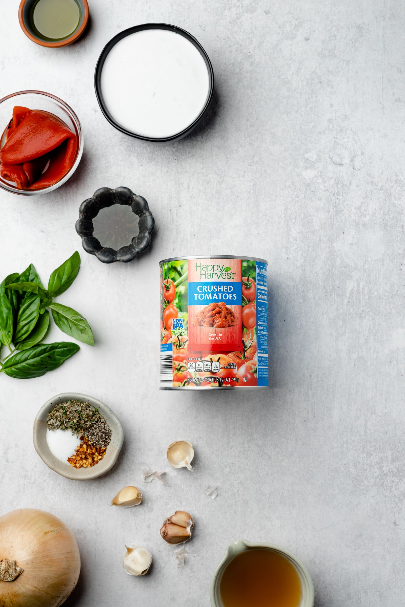 Tomato basil soup ingredients on a gray backdrop.